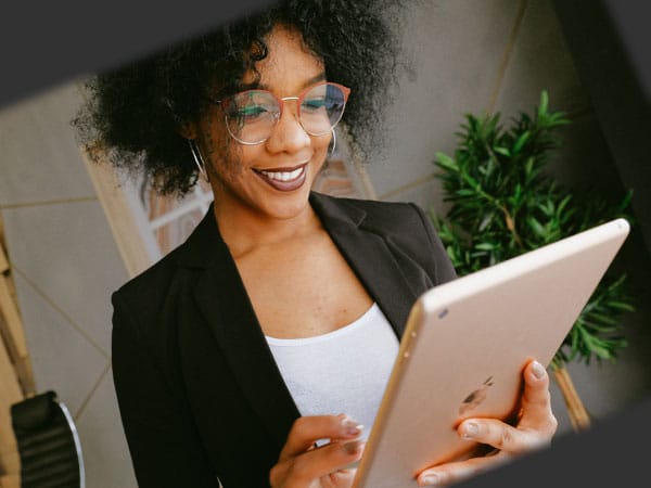 Chica sonriente mirando una tableta. Con una estrategia de marketing de contenidos podrás enganchar a tus usuarios.